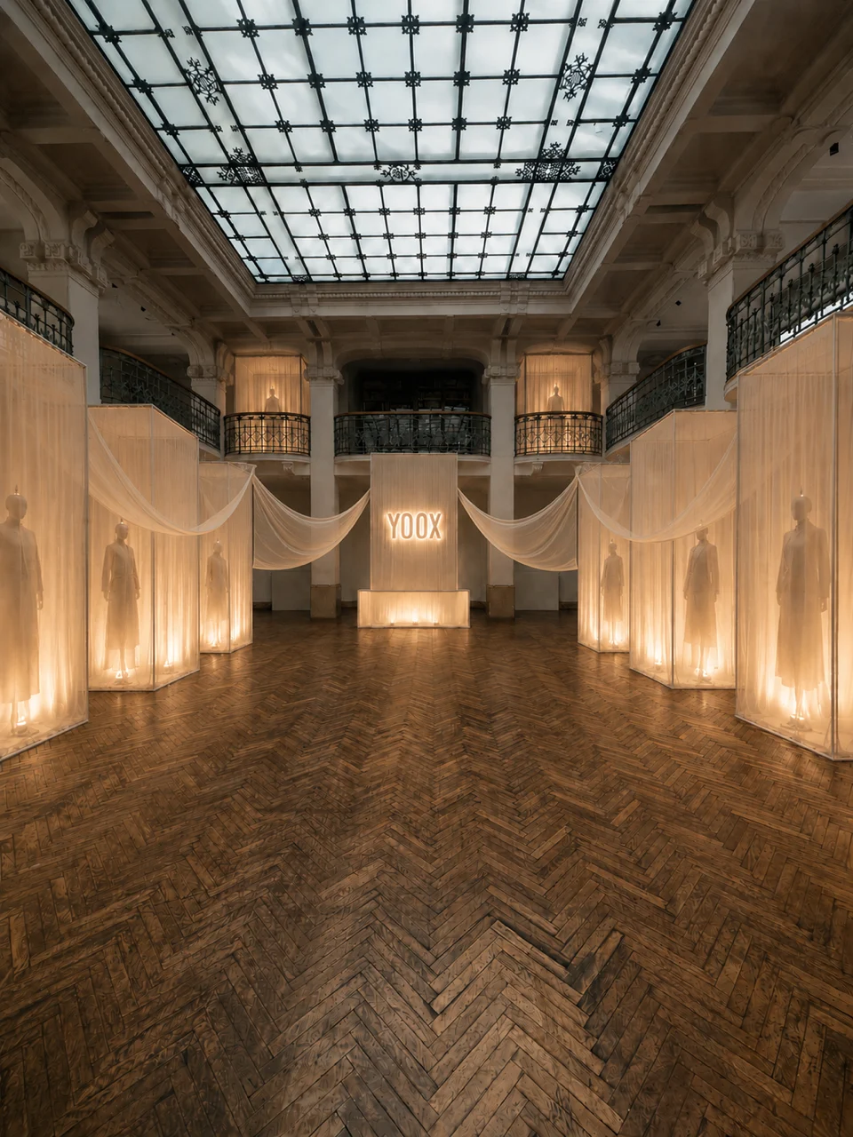 Installazione immersiva YOOX Camerino con capi esposti tra tendaggi luminosi